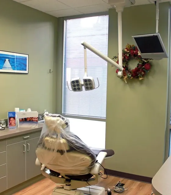 A treatment room with the chair, overhead light and a window.